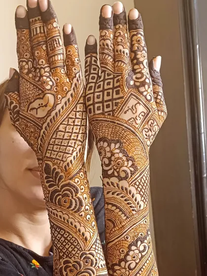 A full back-of-hand design that extends up the arm, featuring a mix of floral, paisley, and geometric patterns.