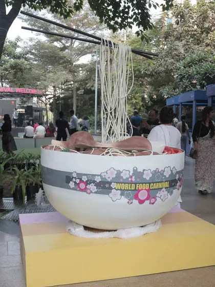 A giant, whimsical noodle bowl installation at the World Food Carnival. These creative, large-scale decorations serve as popular photo spots and add to the event's unique character.