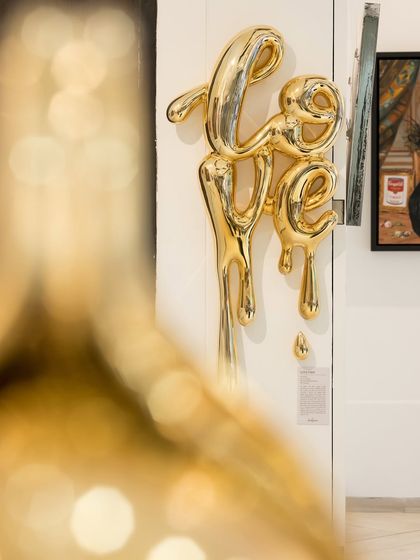 A beautifully composed shot of the 'Love Drip' sculpture with a blurred foreground. This artistic photo highlights the piece as a central element of our gallery's collection.