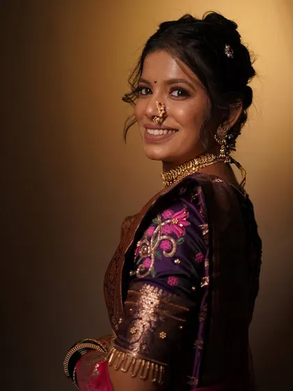 A smiling portrait of the bride in her purple engagement saree. The makeup is glamorous yet elegant, perfect for an evening function.