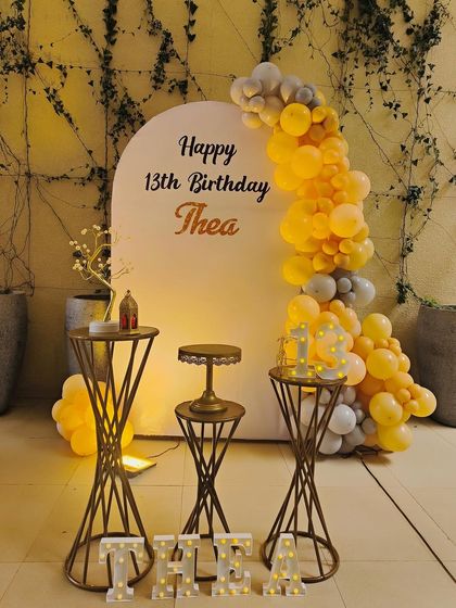 A warm and inviting setup for Thea's 13th birthday. We used a yellow and grey color palette for the balloon garland and paired it with marquee letters for her name and age, creating a personalized and modern look.
