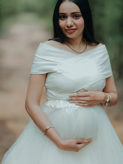 A beautiful portrait of a mom-to-be, cradling her bump. The satin-finish bodice of this white gown adds a touch of luxury.