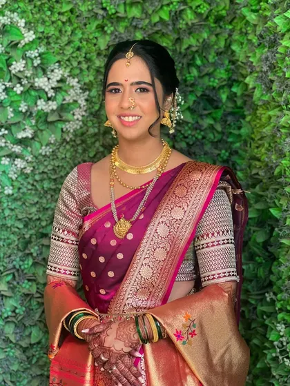A happy portrait of Ramaa, showcasing her complete traditional look against a lovely green backdrop.