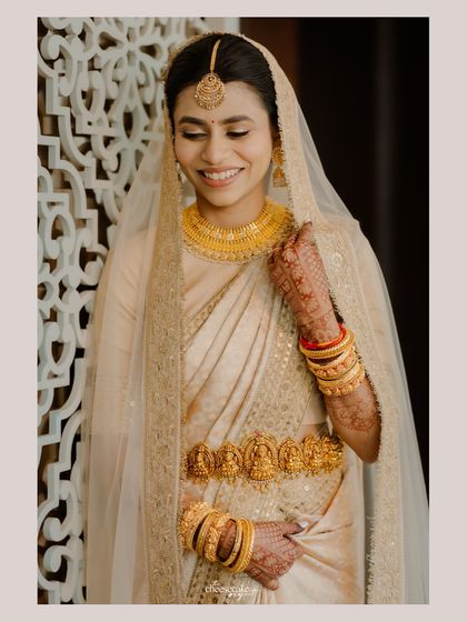 A beautiful Konkani bride in a stunning gold Sabyasachi saree, her smile is radiant.