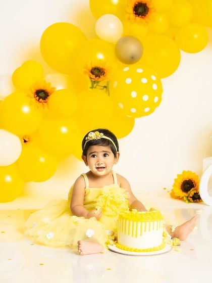 A messy and happy baby is the sign of a successful cake smash! This little one is covered in yellow frosting during her sunny sunflower-themed celebration.