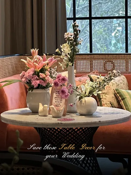 A beautifully styled coffee table with an arrangement of pink and white flowers in modern ceramic vases, showcasing a soft and contemporary aesthetic.
