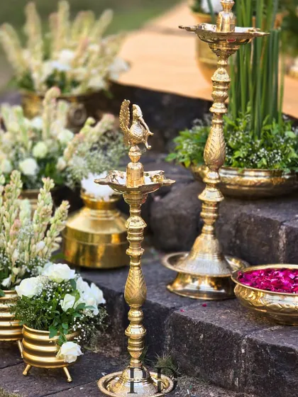 Traditional South Indian brass lamps ('diyas') used as decor elements, adding an authentic and sacred glow to the wedding ceremony.