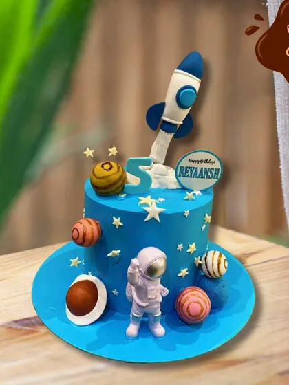 A cake that's out of this world. This space-themed design for a fifth birthday features a blue planet-like cake, an astronaut figure, a rocket ship blasting off, and edible planets.