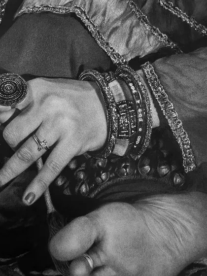 Another detail shot, this time showing the hand, foot, and traditional jewelry. Capturing the texture of the fabric, the metallic shine of the bangles, and the gesture of the hand is key to the story.