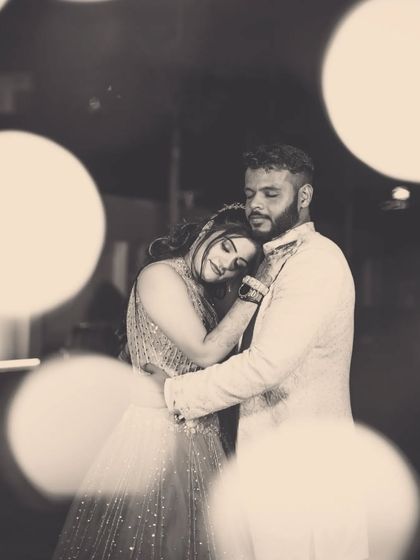 A black and white portrait of a couple embracing, with soft bokeh lights creating a romantic and dreamy atmosphere.