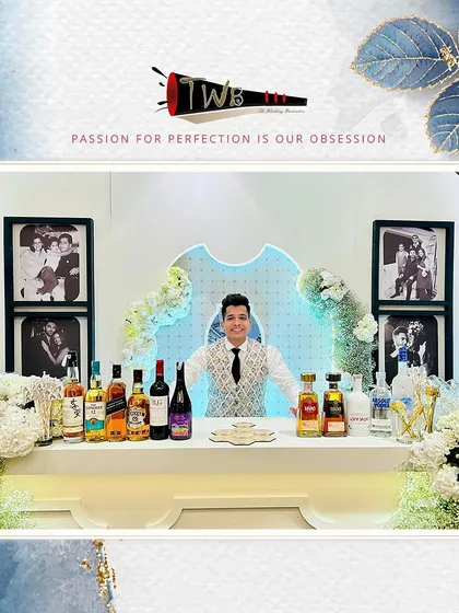 A classic and stylish bar setup for a reception at The Leela Palace, featuring clean white decor, elegant floral arrangements, and professional backlighting to showcase our premium liquor selection.