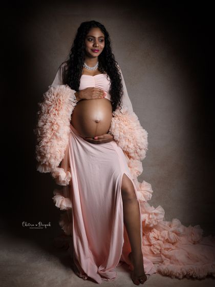 A stunning portrait showcasing the baby bump. This mom-to-be looks powerful and beautiful in a soft pink ruffled gown.