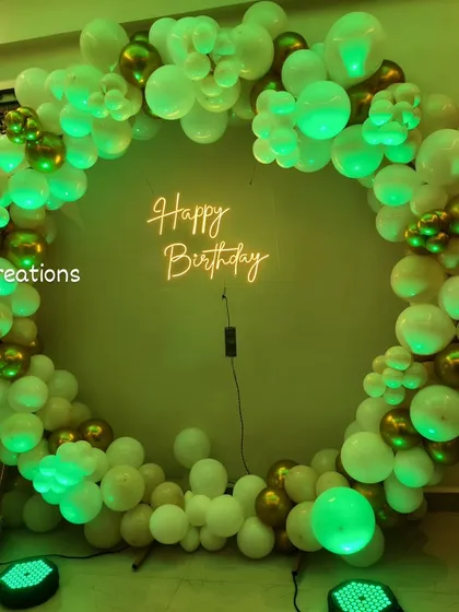 The versatile white and gold balloon circle again, this time under a vibrant green light for a different party vibe.