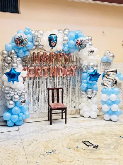 A superhero-themed birthday party featuring Captain America. The balloon arch in blue, silver, and white creates an exciting backdrop for a 5th birthday.