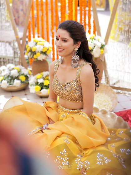 A beautiful solo portrait of the bride, looking radiant and serene amidst the vibrant yellow decor of her Haldi ceremony.
