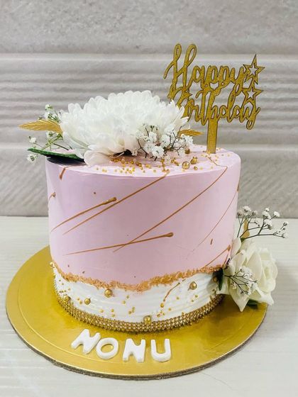A simple and pretty pink cake with delicate gold lines and fresh white flowers, perfect for an elegant birthday.