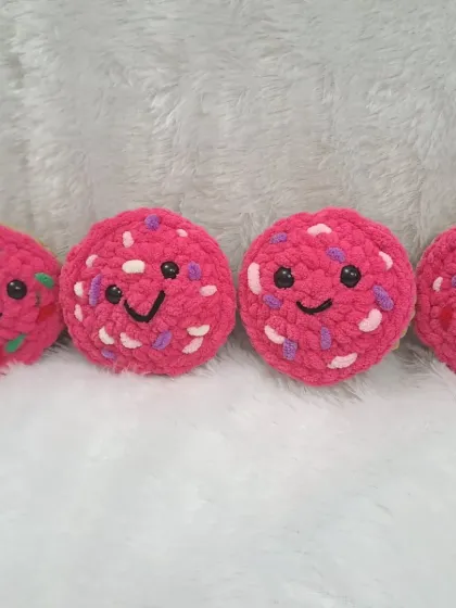 These smiling pink cupcakes are made from soft plush yarn and have colorful sprinkles.
