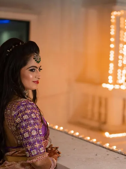 A side profile of the reception hairstyle. The soft waves are pinned back elegantly, allowing the focus to remain on her makeup and stunning jewellery.