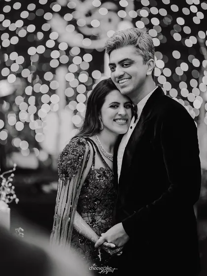 A sweet, smiling portrait of the couple during their cocktail night, with a beautiful bokeh background of fairy lights.
