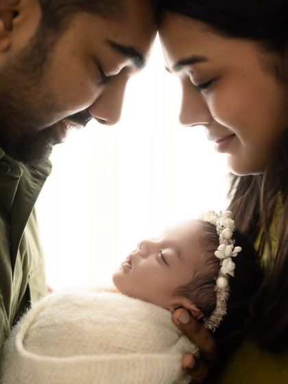 An artistic and intimate portrait of new parents with their baby. The backlighting creates a beautiful glow around the family.