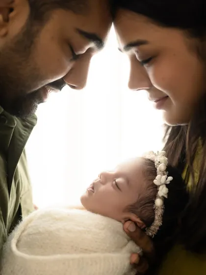 An artistic and intimate portrait of new parents with their baby. The backlighting creates a beautiful glow around the family.