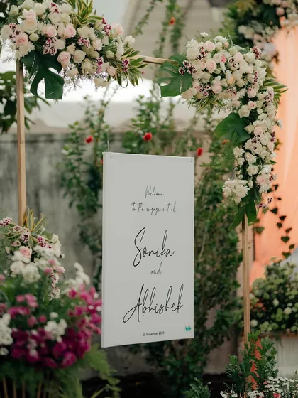 Personal touches make an event unique. For Sonika and Abhishek's engagement, we designed this elegant welcome sign, framed with an arch of exotic white and pink flowers that set a romantic tone from the moment guests arrived.