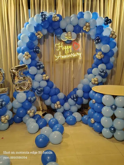 Here is a grand heart-shaped balloon arch I created for a 25th anniversary celebration. The blue and silver color scheme, combined with the large '25' foil balloons and a 'Happy Anniversary' neon sign, makes for a perfect photo backdrop at any party venue.