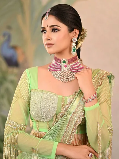 A beautiful reception look in a light green saree, complemented by a modern choker necklace. The painted backdrop adds a touch of sophistication and artistry.