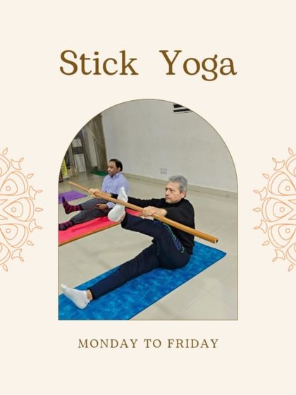 Stick yoga is excellent for improving alignment and balance. In this photo, a student uses the stick for support in a standing leg stretch, helping him maintain a straight spine and deepen the posture.
