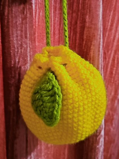 The lemon pouch hanging, showing off its round shape and drawstring closure. It's a great little project that brings a bit of summer fun to your accessories.