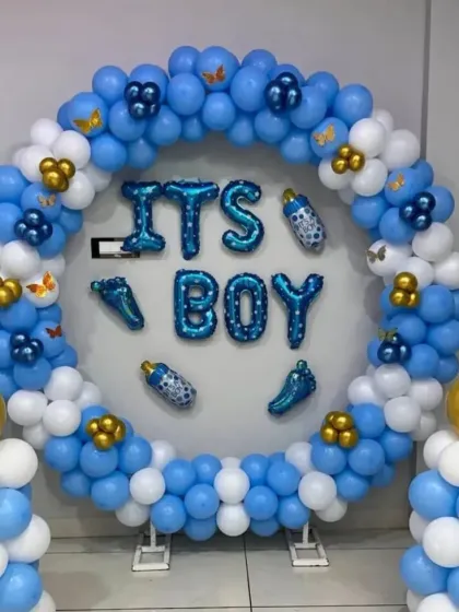 A bright and cheerful "It's a Boy" balloon ring. The blue and white balloons are accented with gold clusters and baby-themed foil balloons, creating a perfect photo spot.