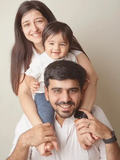 A classic family pose with the little one perched on dad's shoulders. Their coordinated outfits and bright smiles make for a picture-perfect memory.