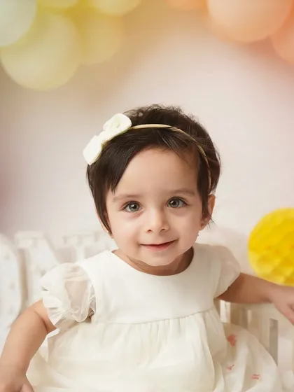 A sweet, gentle smile from the one-year-old. Her delicate dress and the soft lighting make this a truly angelic milestone portrait.