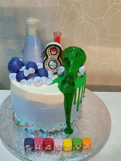 A cake with great chemistry. This science-themed cake features bubbling beakers, overflowing green slime, and colorful letter blocks.