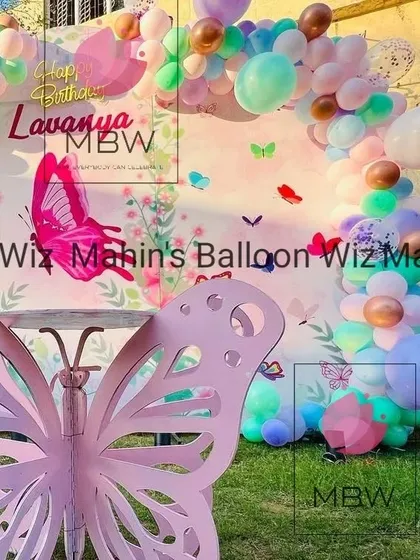 An outdoor butterfly party setup, featuring a large pink butterfly prop that creates a fantastic photo opportunity.
