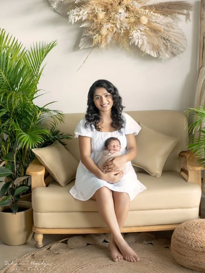 A mother and her newborn baby, sitting on the couch in our cozy, plant-filled studio.