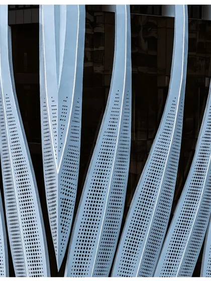 A detailed view of the perforated calligraphic facade of the ID Origins tower. This element is not just aesthetic; it is a performance-driven screen designed to reduce solar glare for the commercial floors while maintaining a lightweight, elegant appearance.