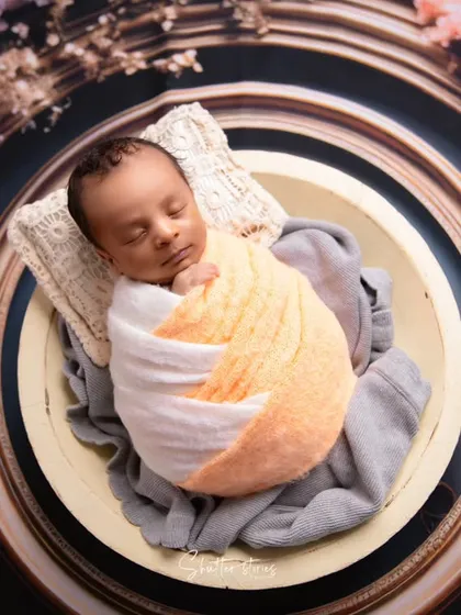 A tighter shot of the frame-themed setup, showing the baby's peaceful pose and the interesting color combination of the wrap.