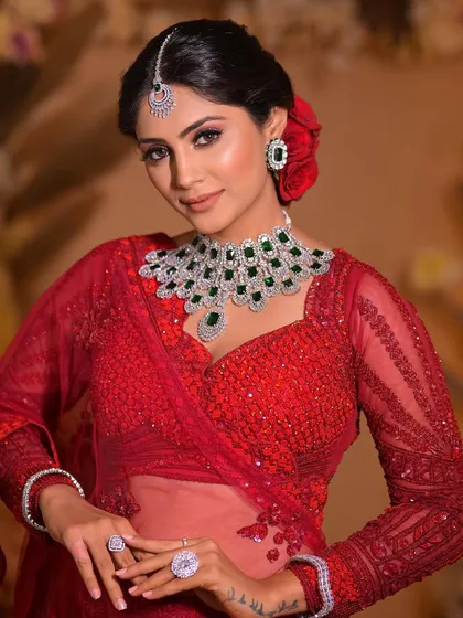 For this bridal look, I paired a classic red lehenga with a dramatic smokey eye and a statement diamond and emerald necklace. The red roses in her hair tie it all together.