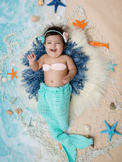 Giggles and waves from this happy little mermaid. The crocheted tail is a perfect prop.