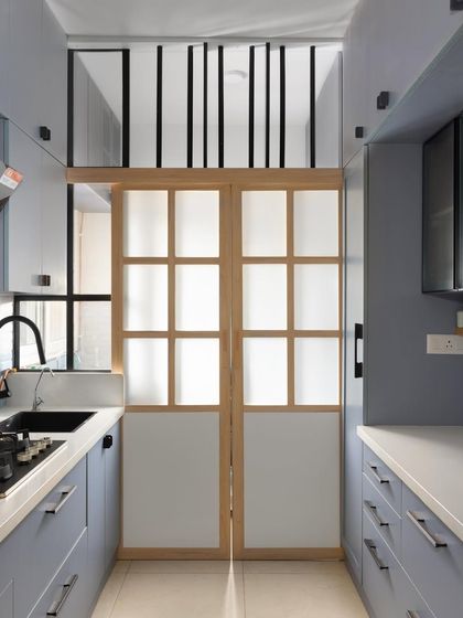 To optimize space in this compact kitchen, I installed a sliding door with frosted glass panels to separate it from the utility area. This maintains an open, airy feel while hiding the functional space.