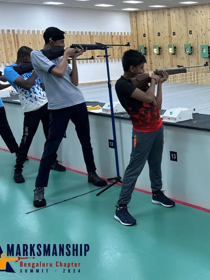 A close-up of young athletes during the Open Sight Rifle competition, demonstrating the concentration and form required in precision shooting sports.
