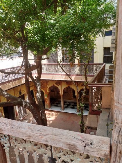 Looking down into the courtyard from a restored wooden balcony, a perspective that highlights the traditional inward-looking architecture of the haveli.