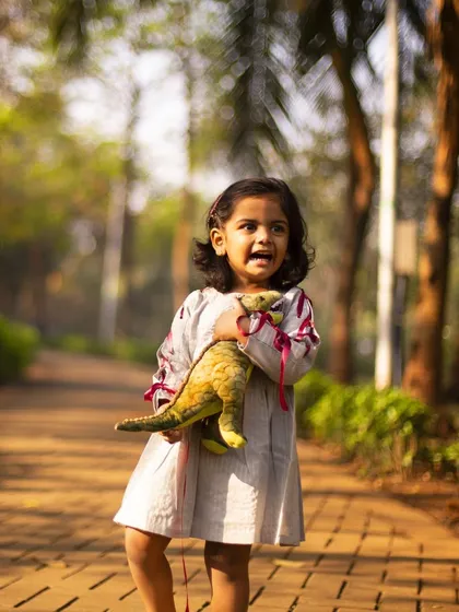 A smiling angel from heaven who came to steal our hearts. This photo from her third birthday series captures her bright personality and love for her favorite dinosaur toy.