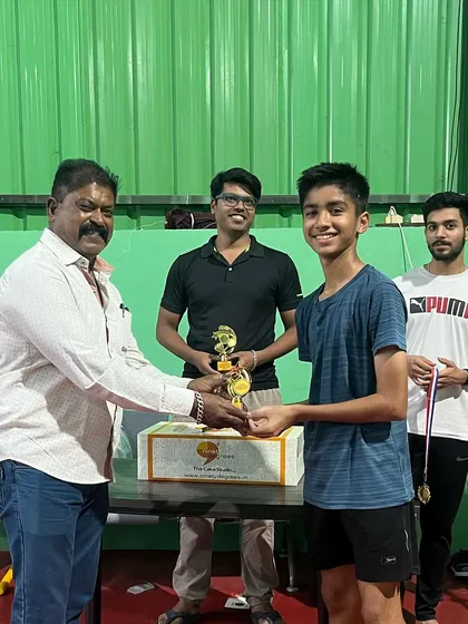 A young champion receives his trophy at our in-house league tournament. My events cater to various age groups, ensuring fair and exciting competition for all players, which is crucial for player development.