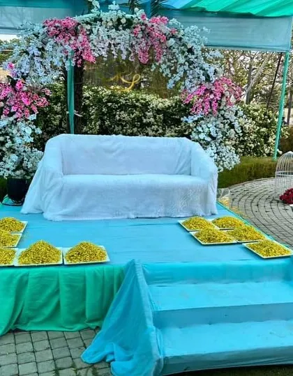 This poolside Haldi stage features a beautiful arch of white and pink flowers. The setup is designed for the ceremony rituals, with plates of turmeric paste ready for the celebration to begin at this resort venue.