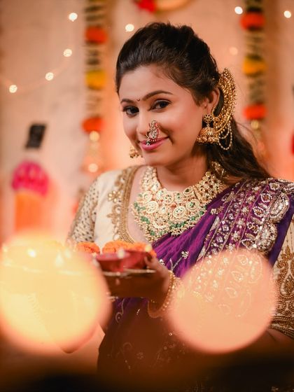 The warm glow of the diyas illuminates the intricate jewellery and the rich colour of the purple saree.