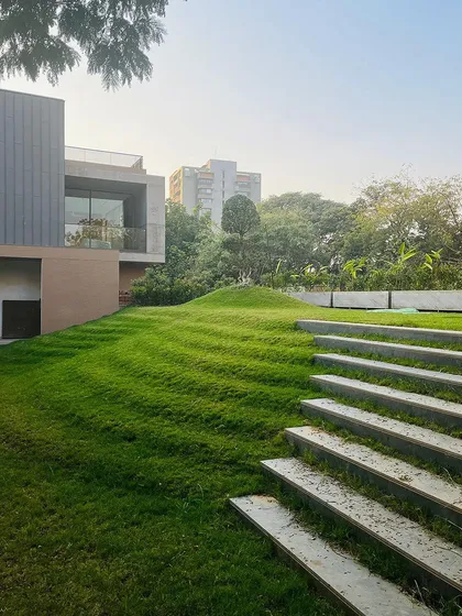 We see opportunity in every surface. Here, we transformed a functional carport roof into "The Rising Green," a sloping lawn that merges with the surrounding landscape. It’s a perfect example of our biophilic approach, where nature and structure become indistinguishable.
