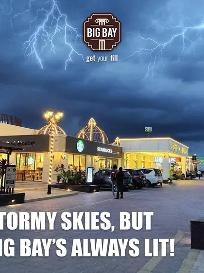 Stormy skies, but Big Bay's always lit. This image shows our campus glowing warmly under a dramatic, lightning-filled sky, a beacon for travelers.