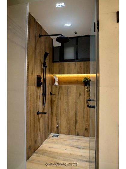 A master bathroom featuring a wooden-finish tile in the shower cabin for a warm, natural feel. The all-black shower fittings add a touch of modern, industrial chic.